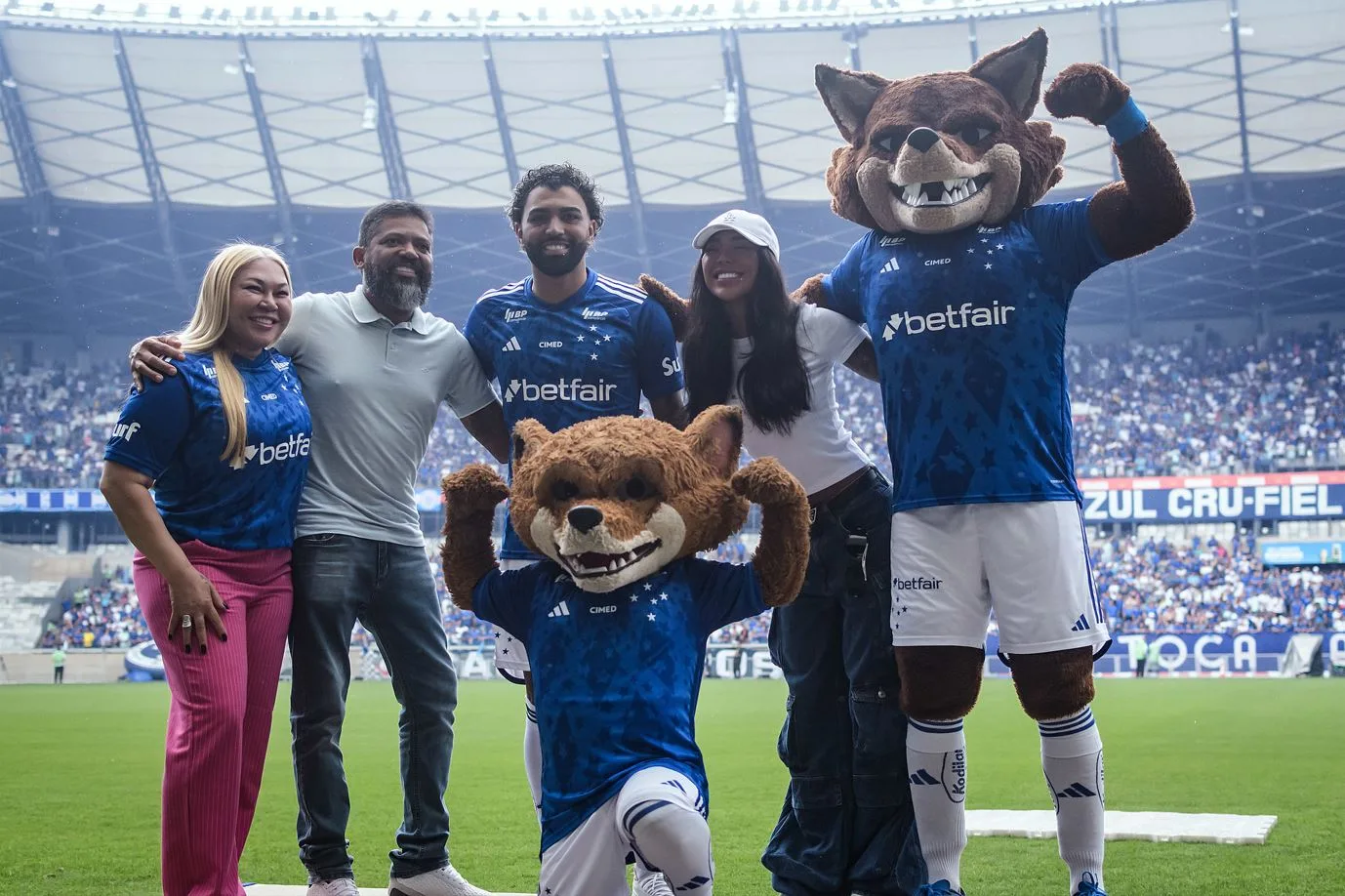 Grupo com torcedores e mascote em estádio de futebol