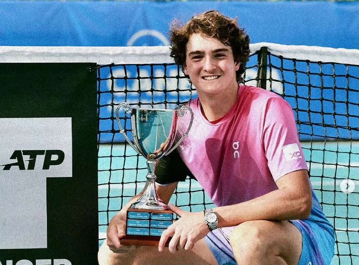Jovem tenista com troféu ATP ao lado da rede
