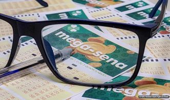 A lente de um óculos com armação preta destacando o Bilhete de aposta na Mega-Sena