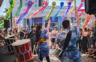 Apresentação de taiko durante o Festival Tanabata Matsuri em Belo Horizonte, com músicos em trajes tradicionais japoneses tocando tambores, cercados por público atento e enfeites coloridos pendurados, representando a tradicional celebração da cultura nipônica.