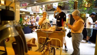 Visitantes degustam café artesanal em estação móvel durante o Festival Tomei Gosto por Café, no Mercado de Origem, em Belo Horizonte, em ambiente descontraído com produtores locais e experiências sensoriais voltadas ao universo do café especial mineiro.