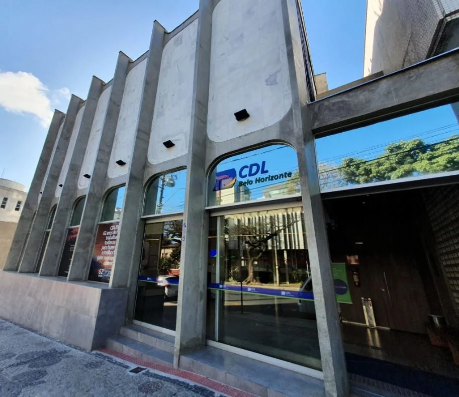 Fachada da sede da CDL Belo Horizonte, localizada na área central da capital mineira, com arquitetura moderna e grandes vitrines de vidro refletindo o entorno urbano.