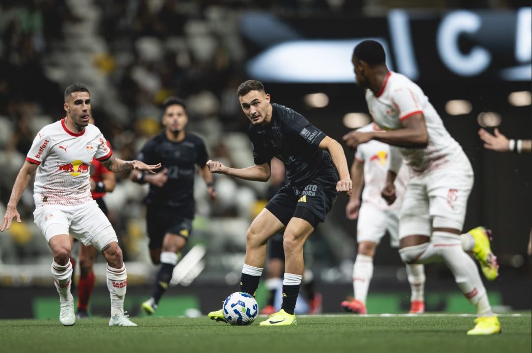 Jogador do Atlético Mineiro em ação com a bola no meio-campo, cercado por atletas do Bragantino durante partida na Arena MRV.