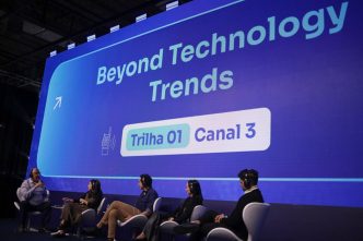 Painel com cinco especialistas sentados em cadeiras modernas, discutindo tendências tecnológicas no palco do Latam Retail Show, com uma grande tela de LED ao fundo exibindo o tema “Beyond Technology Trends – Trilha 01, Canal 3”.