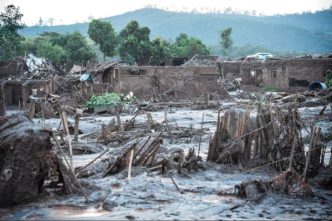 Área completamente destruída pela lama tóxica do rompimento da barragem de Fundão, em Mariana (MG), com casas soterradas e vegetação devastada.