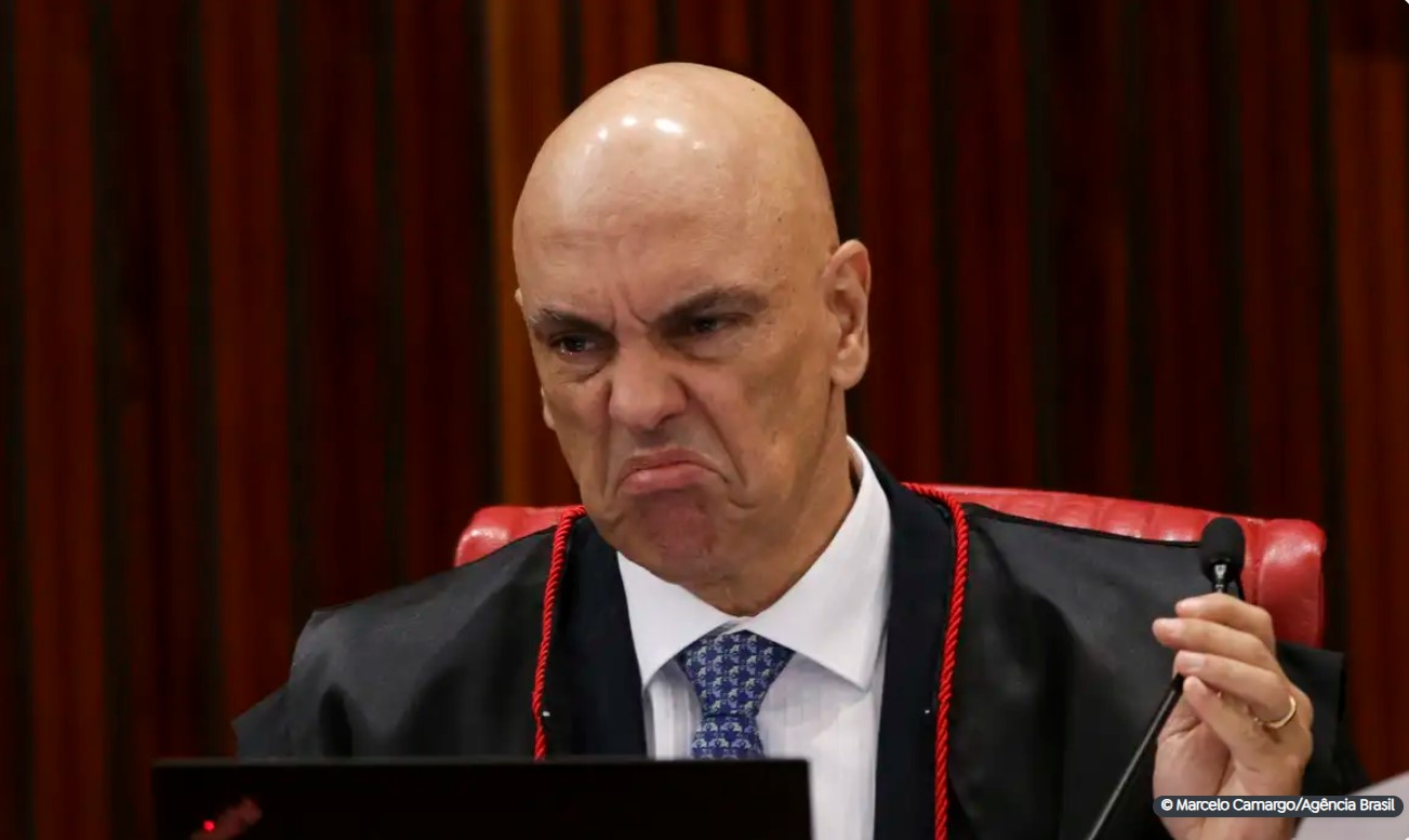 Ministro Alexandre de Moraes com expressão severa durante sessão no Supremo Tribunal Federal, vestindo toga preta e gravata azul.
