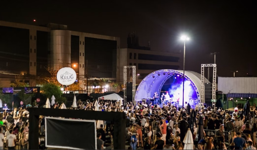 Grande público prestigia show noturno ao ar livre durante evento gastronômico da Churrascaria Porcão em Belo Horizonte, com palco iluminado e estrutura profissional ao fundo.