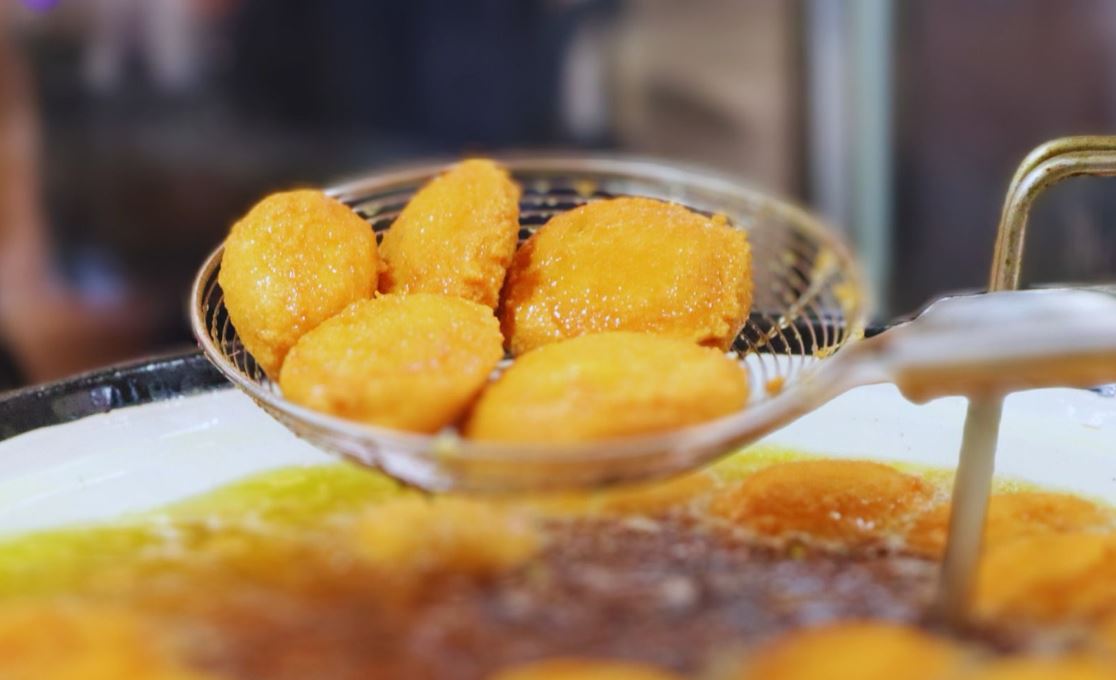 Acarajés dourados sendo escorridos do óleo em peneira metálica durante preparo típico nordestino na Feira Gastronômica de Santa Tereza.