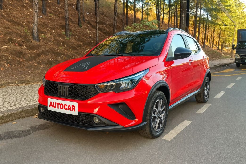 Fiat Argo Trekking 2026 vermelho estacionado em rua arborizada, com destaque para o design frontal renovado, faróis Full-LED e detalhes em preto brilhante.