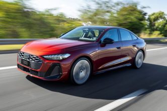 Novo Audi A5 2025 em movimento, na cor vermelho granadina, exibindo design renovado, rodas esportivas e faróis full-LED em rodovia.
