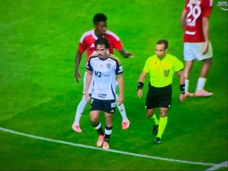 Jogador do Atlético-MG caminha cabisbaixo após lance polêmico, observado de perto pelo árbitro e jogadores do Internacional.