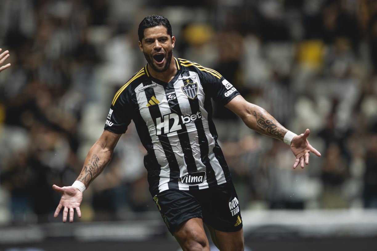 "Hulk comemora com intensidade seu gol histórico pelo Atlético Mineiro na Arena MRV, vestindo o uniforme alvinegro com patrocínios visíveis."