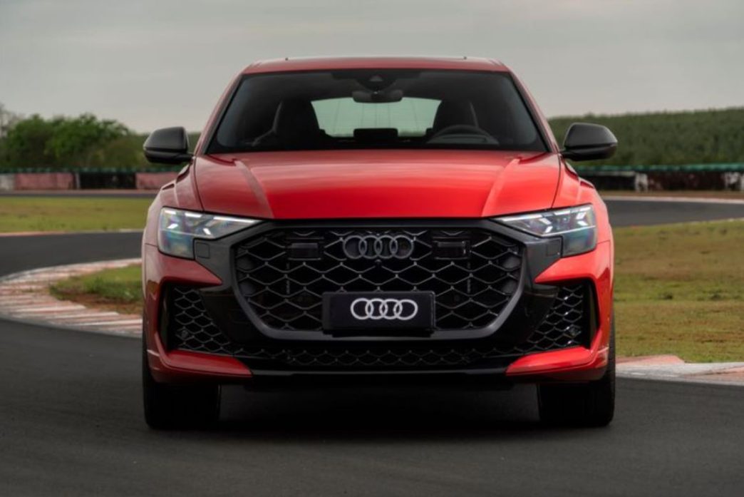 Frontal do novo Audi RS Q8 Performance 2026 em vermelho vibrante sobre pista, destacando grade Singleframe preta e faróis Matrix LED.