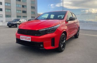 Fiat Cronos Drive 1.3 2026 vermelho em destaque, com novo design frontal, faróis full LED e rodas esportivas, estacionado ao ar livre.